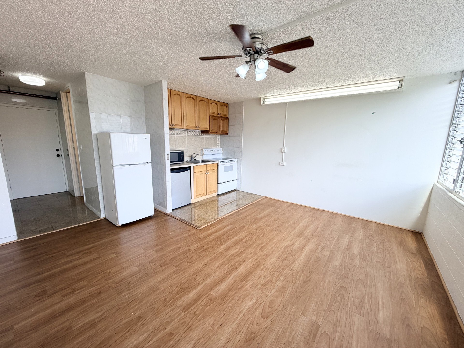 A room with a ceiling fan and wooden flooring.